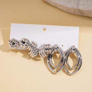 Detail of silver earring set featuring textured hoops and studs on display card