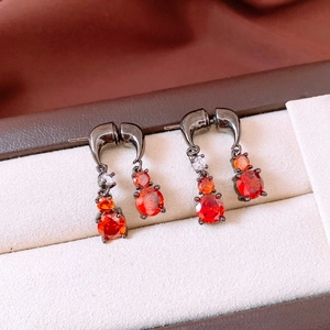 Macro shot of gunmetal drop earrings with gradient orange zircon stones in a jewelry box