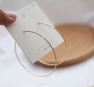 Close-up of minimalist large golden hoop earrings on a display card from Korea