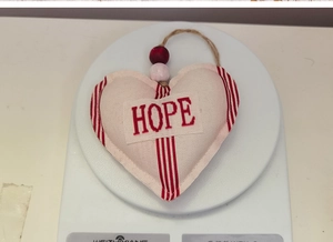 Detail of cream fabric heart ornament with red stripes and HOPE text embroidery