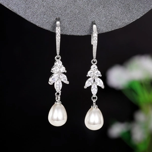 Detailed view of teardrop pearl earrings with zircon-inlaid floral accents and silver hooks