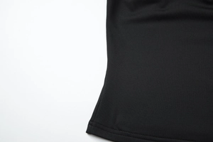 Detailed close-up of the black knit fabric texture and hem stitching on the top