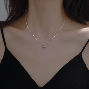 Close-up of rose gold necklace featuring five multi-colored gemstone rings on the chain