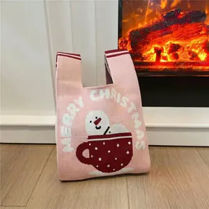 Pink Christmas knit tote bag with snowman pattern and Merry Christmas text by fireplace