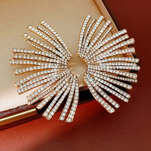 Close-up of golden fan-shaped earrings with micro-paved rhinestones in a jewelry box