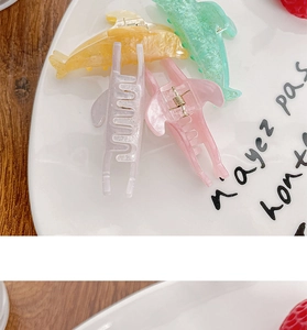Macro shot of candy-colored dolphin hair clips with glitter finish in a ceramic dish