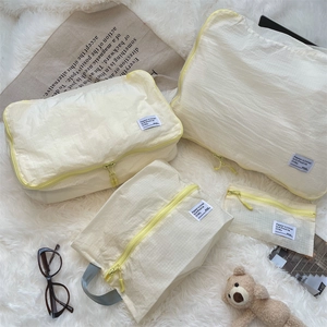 Detail of 4-piece cream travel organizer set with yellow zippers on soft white rug