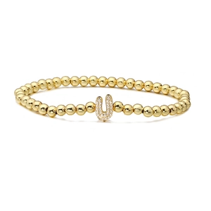 Macro detail of gold beaded stretch bracelet with micro-paved zircon letter U charm