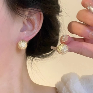Detail of matte gold textured ball earrings featuring a brushed metallic finish