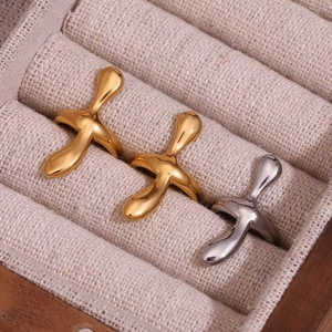 Polished 18K gold and silver cross rings with liquid metal texture in a jewelry box