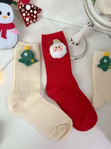 Detail of Christmas socks with 3D Santa and tree plush charms on ribbed cotton fabric