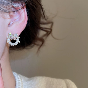 Close-up of bow knot pearl earrings on a model showing elegant zircon and metal details