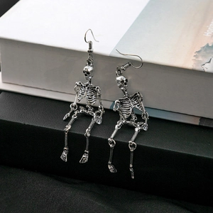 Gothic silver skeleton earrings with blue tulle on vintage book prop background