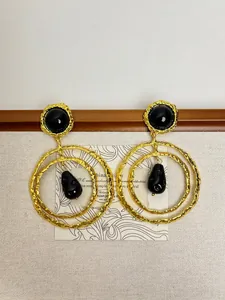 Gros plan de boucles d'oreilles double anneau doré martelé avec gouttes noires