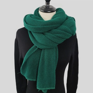 Close-up of thick dark green knit scarf showing detailed chunky braided texture