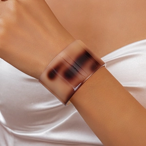 Detail of tortoise shell acetate wide cuff bracelet with smooth amber texture on model