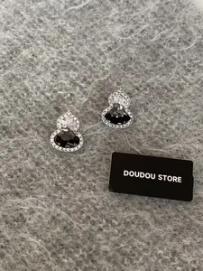 Detail of silver gourd stud earrings with black and white crystal inlay on plush fabric