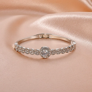 Silver vintage heart bracelet with diamonds on champagne silk fabric background