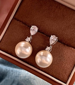 Vue macro de boucles d'oreilles perles champagne et zircon dans un écrin à bijoux