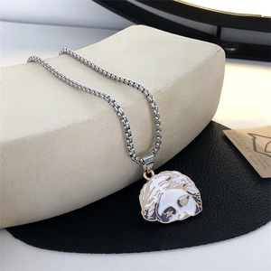 Detailed close-up of a white enamel poodle puppy pendant on a silver box chain necklace