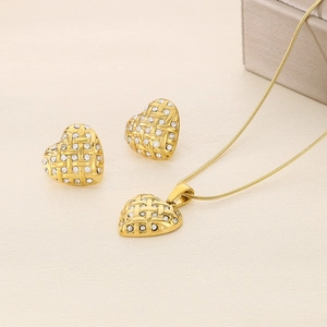 Golden heart jewelry set with woven texture and crystals on soft beige fabric