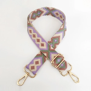 Detail of geometric ethnic jacquard bag strap with gold metal hooks and purple diamond pattern