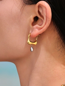 Macro shot of two-tone irregular U-shaped hoop earrings with water drop pendants on model