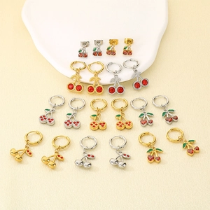 Detailed view of creative cherry earrings featuring red zircons and green enamel leaves