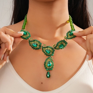 Detail of vintage ethnic style teardrop necklace with emerald green beads and crystal inlay