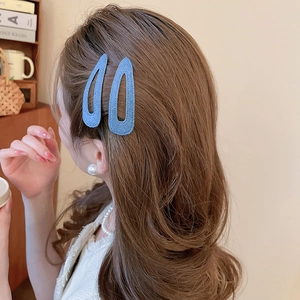 Detail view of denim fabric star and drop hair clips on wavy brown hair