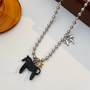 Dettaglio di collana vintage con perline, ciondoli a forma di cavallo nero e stella d'oro