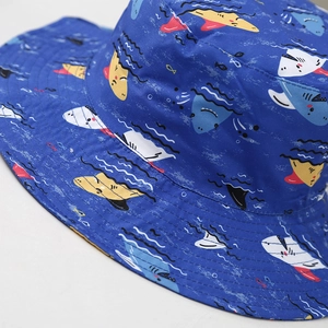 Close-up of bright blue kids sun hat with colorful cartoon shark print and wide brim