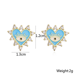 Detail view of heart-shaped evil eye earrings with zircon pavé and blue enamel finish
