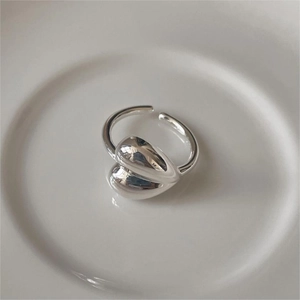 Detailed view of silver heart-shaped ring with polished finish on white ceramic tray