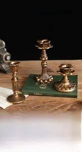 Detail van vintage bronzen kandelaars met lotusrand op een donkere houten tafelblad