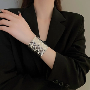 Macro shot of silver irregular textured metal cuff bracelet against black fabric