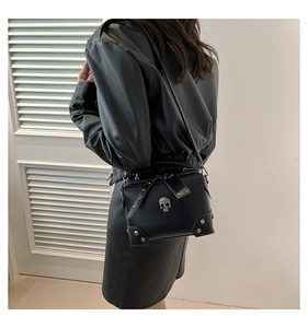 Detail of black PU leather shoulder bag with silver skull ornament and metallic rivets