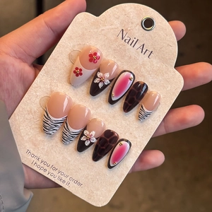Detail of zebra and leopard print press-on nails with 3D floral accents and golden beads