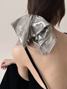 Macro detail of a large silver metallic scrunchie with shiny pleated texture on ponytail