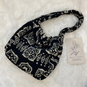 Detail of plush black and white geometric pattern bag with silver magnetic closure
