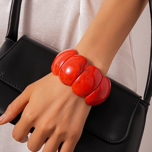 Statement red marble texture acrylic geometric bracelet on model's wrist with fashion styling