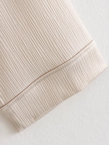 Vue macro du tissu plissé beige et coutures de précision sur l'ensemble blazer