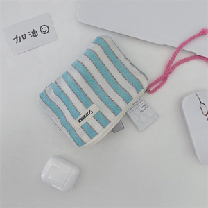 Detail of blue striped canvas pouch with pink wrist strap and zipper on office desk