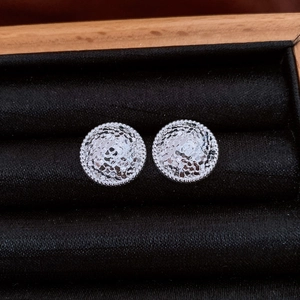 Détail de boucles d'oreilles rondes plissées argentées dans un écrin en velours noir