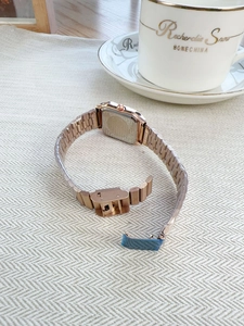 Detail of rose gold ladies' watch metal strap and clasp with protective film on tablecloth