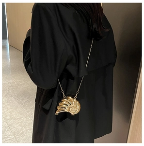 Nahaufnahme der goldenen Schnecken-Abendtasche mit Metallkette auf schwarzem Blazer