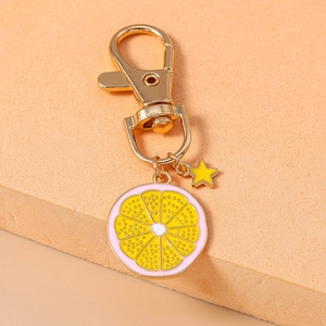 Close-up of lemon slice keychain with pink border, gold lobster clasp and star charm