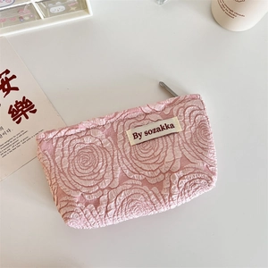 Detailed macro of pink embossed rose texture and branded label on a zipper pouch