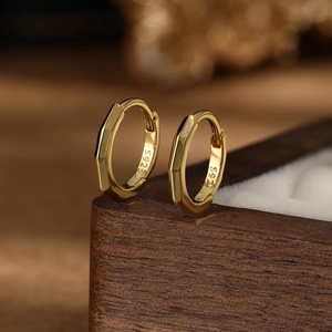 Detail view of gold S925 sterling silver hoop earrings with geometric facets and hallmark