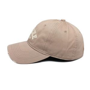 Dettaglio del cappello da baseball kaki con ricamo bianco e finitura vissuta sulla visiera